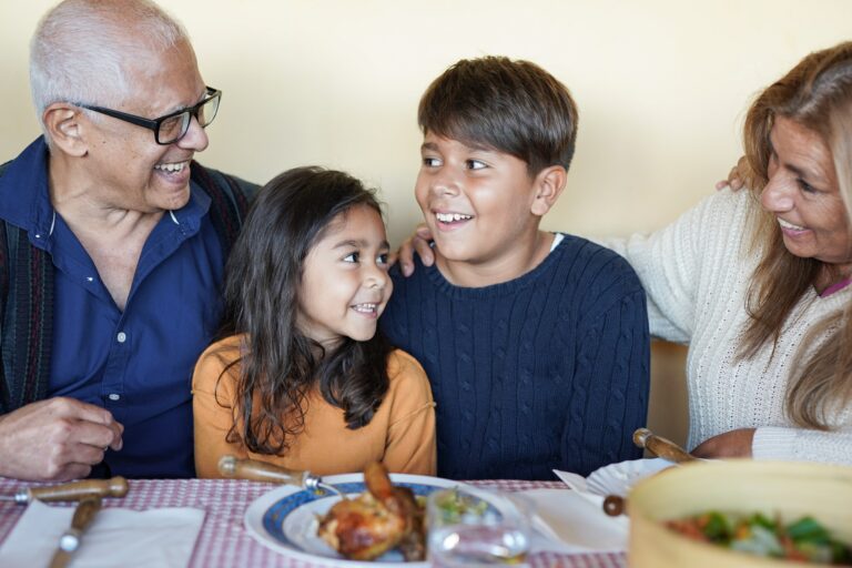 Happy latin grandparents eating lunch with grandchildren at home